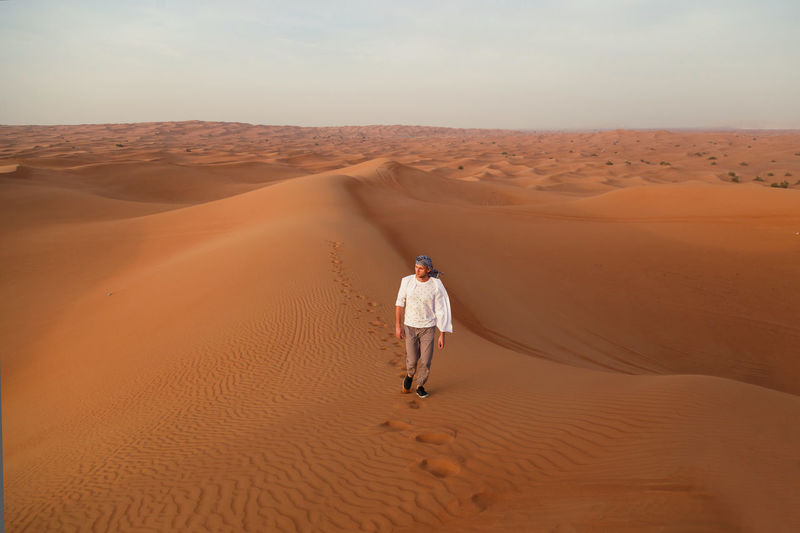 High angle view of man on sand dune in desert against sky
