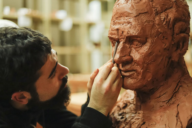 Focused sculptor finishing a clay head