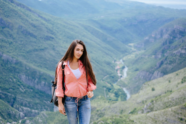 Portrait of beautiful woman standing against mountain
