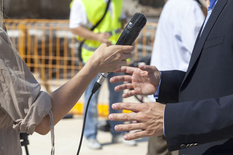 Cropped hand of female journalist interviewing businessman