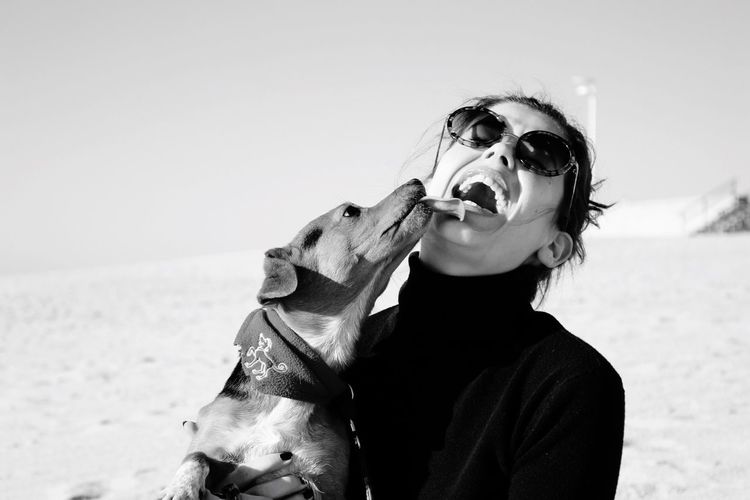 Cheerful woman playing with dog at beach