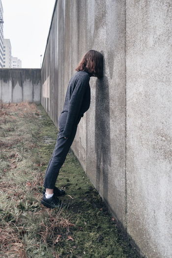 Side view of woman leaning against wall