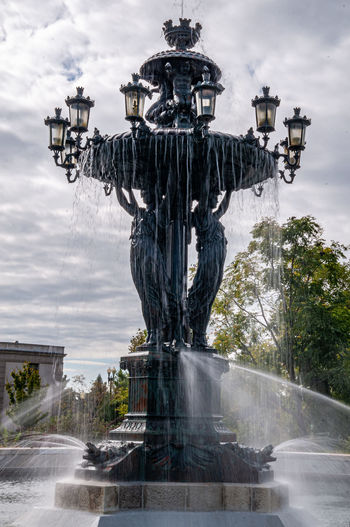 Fountain by statue against sky