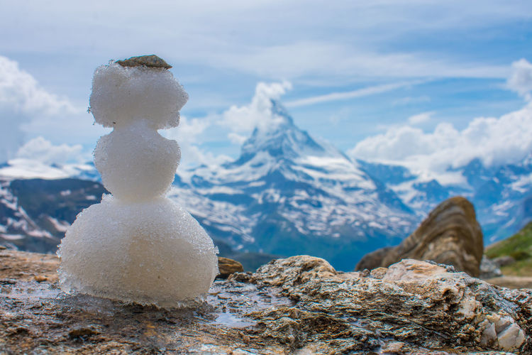 Close-up of snowman on rock against iconic snow capped mountain matterhorn in the background