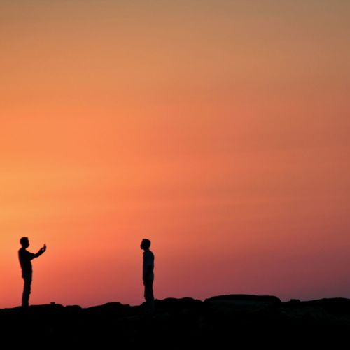 Silhouette of people standing on landscape at sunset