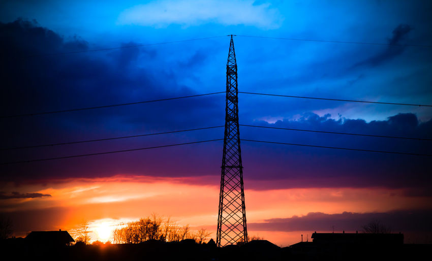 Low angle view of silhouette electricity pylon against sky during sunset