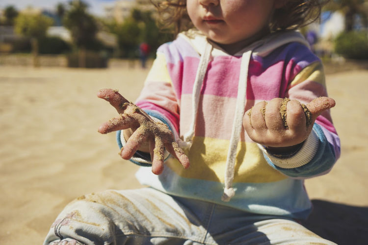 Midsection of girl playing with sand on beach