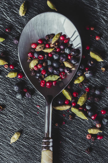 Beautiful detail of a spoon and spices; red pepper, cardamom, juniper.