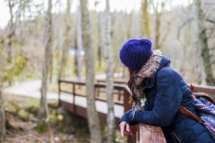 Woman leaning on footbridge during winter