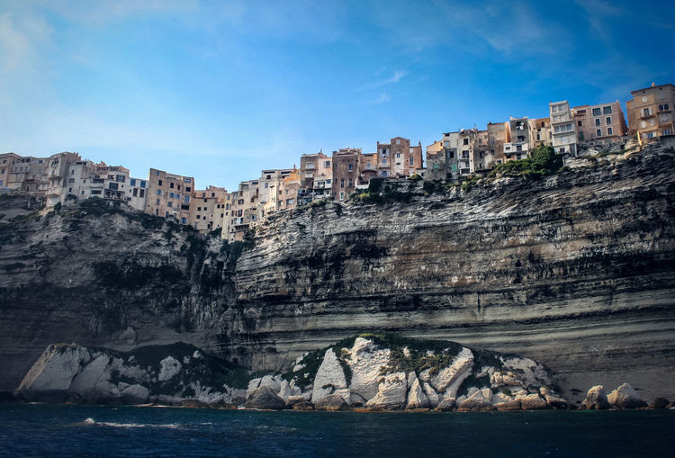 View of sea and cliffs in bonifacio against cloudy sky