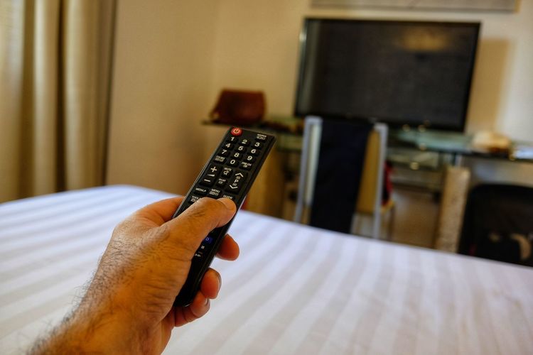 Cropped hand of man holding remote control at home