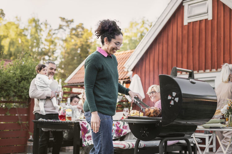 Man and woman standing on barbecue grill in yard