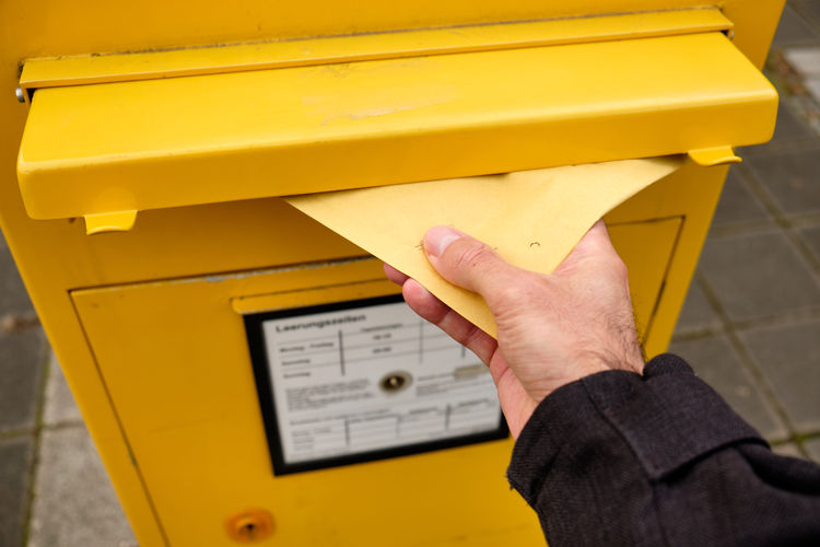 Cropped hand inserting letter in mailbox