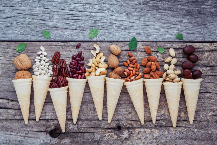 Directly above view of nuts and beans with ice cream cones on wooden table