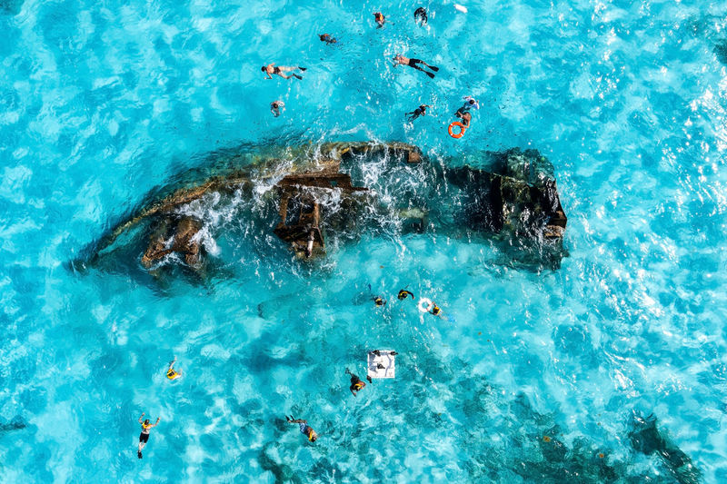 People snorkelling around the ship wreck near bahamas in the caribbean sea.