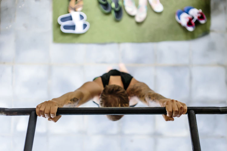 Overhead view of man hanging on gymnastics bar at gym