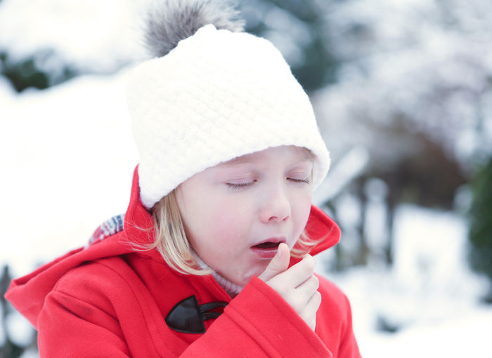 Close-up of cute girl coughing during winter