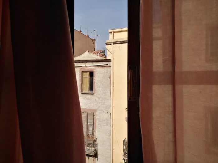Buildings against sky seen through window old palace sardinia 