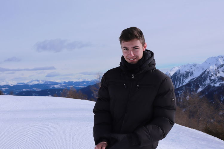 Portrait of young man standing on snow covered mountain