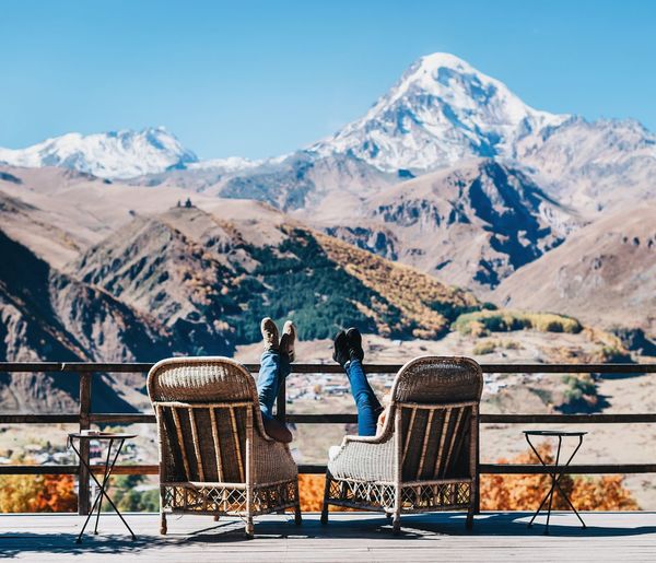 People relaxing against snowcapped mountain and clear blue sky