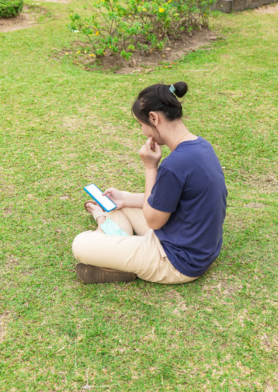 Side view of young woman sitting on grass