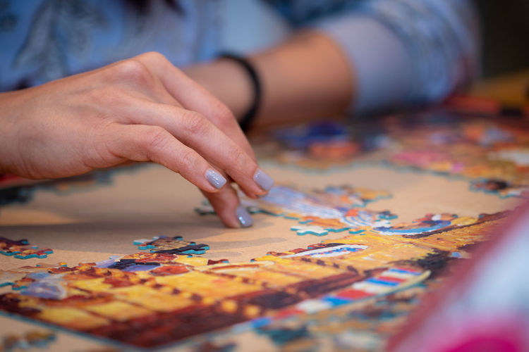 Midsection of woman playing jigsaw puzzle on table