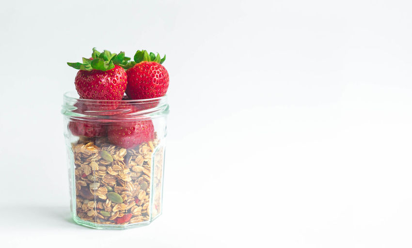 Close-up of strawberries in glass jar against white background