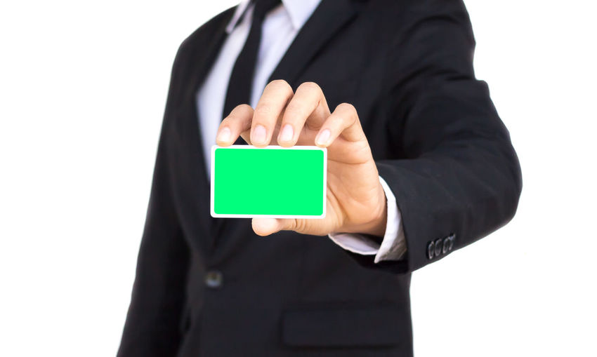 Midsection of businessman holding blank card against white background