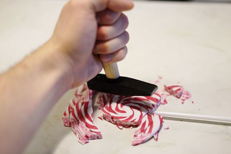 Close-up of hand crushing lollipop