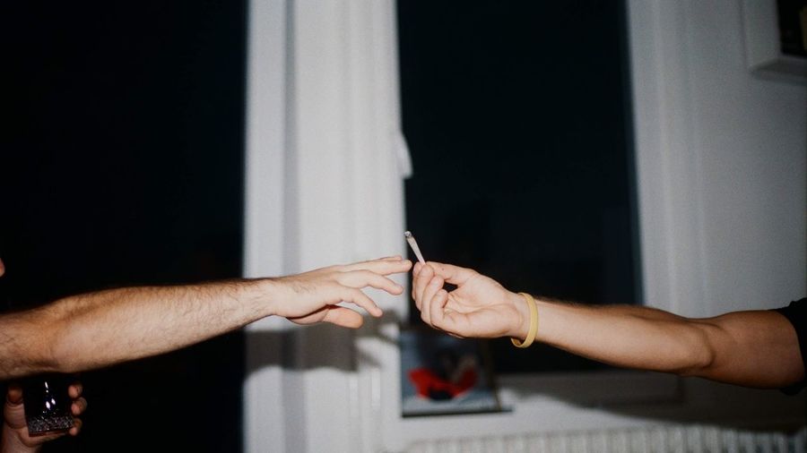 Cropped hand of man passing marijuana joint to friend