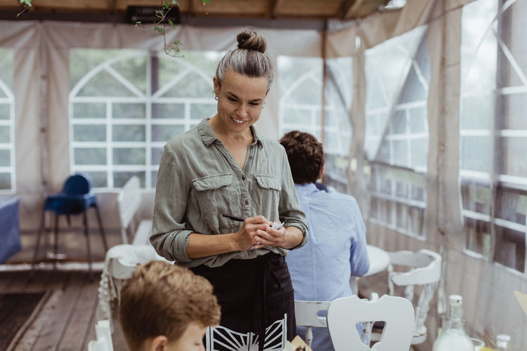 Female owner taking order from customer while sitting in restaurant