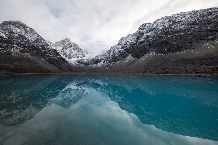 Blue glacial mountain lake in front of rocky snowcapped mountain range