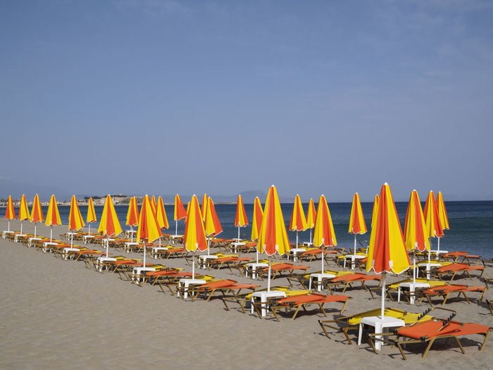 Deck chairs on beach against clear blue sky