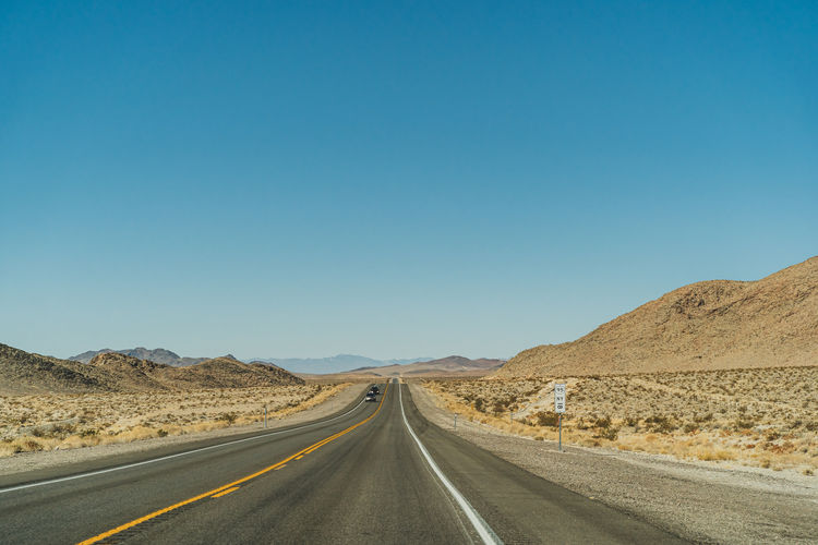 Empty road in desert against clear sky