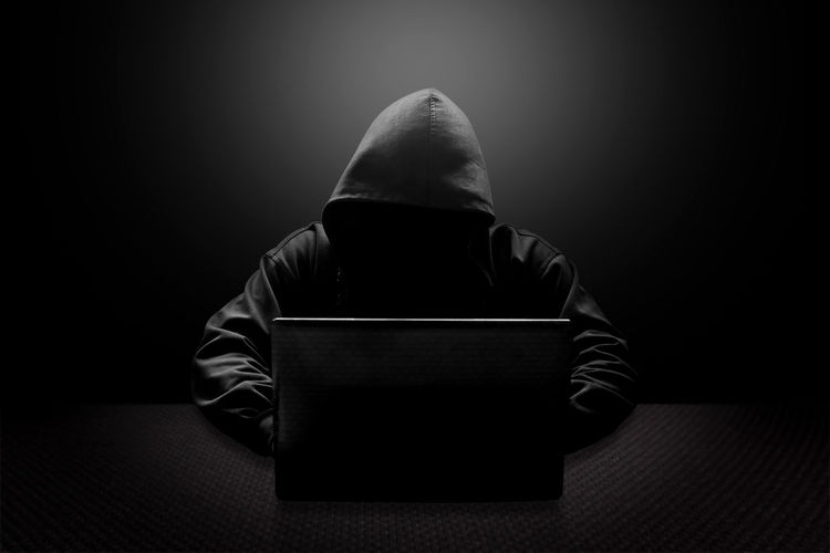 Hacker using laptop over black background