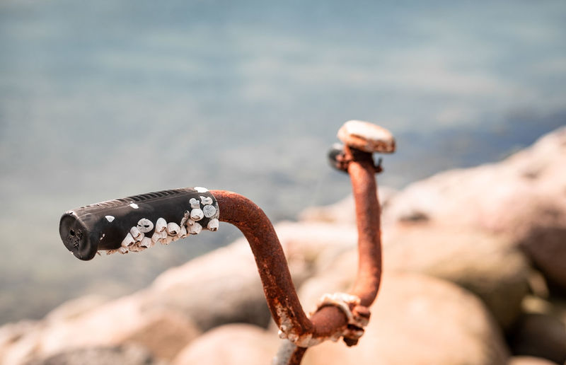 Close-up of rusty handlebar against sea