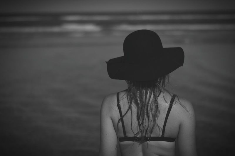 Rear view of young woman in sun hat at sea shore