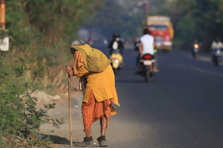Rear view of monk standing on road in city