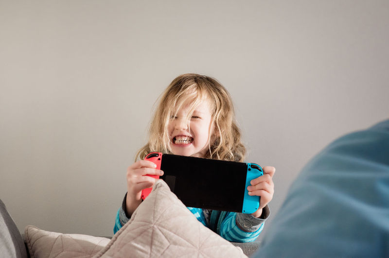 Young girl pulling faces whilst playing nintendo switch at home