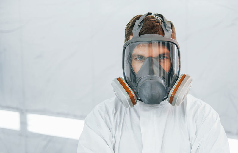 Portrait of man in the protective mask. worker in uniform is in the auto service.