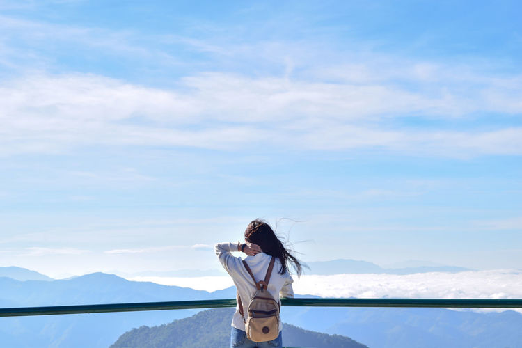 Rear view of woman standing against mountains at observation point