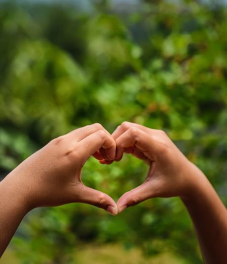 Woman making love heart shape with their hands