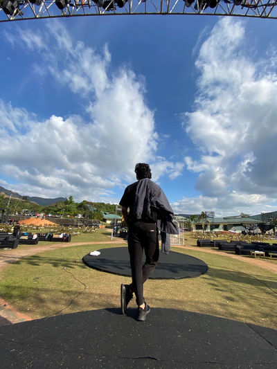 Side view of man standing on field against sky