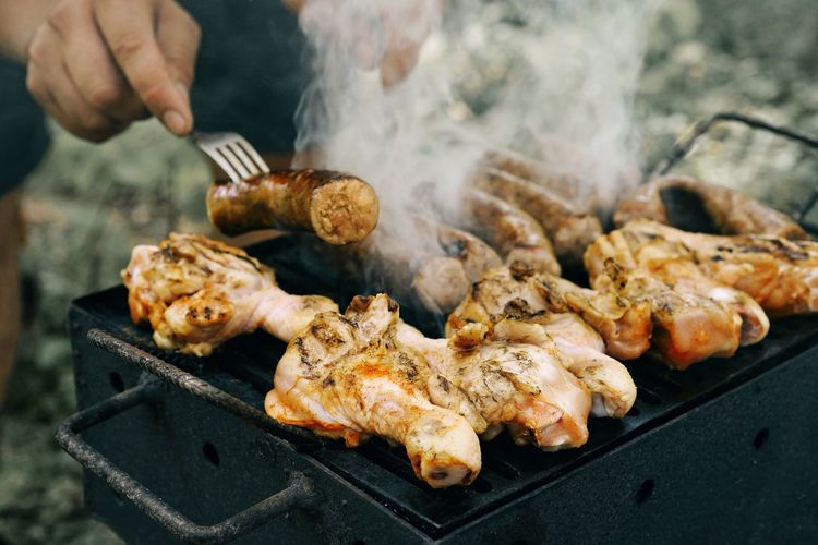 Cropped image of man grilling meat on barbecue grill