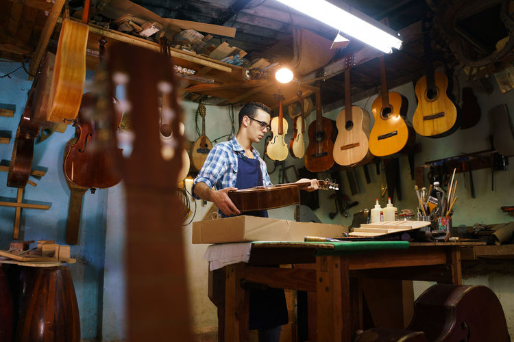 Low angle view of man holding guitar in workshop