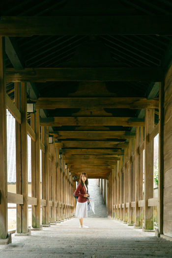Portrait of young woman standing at colonnade
