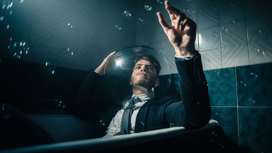 Man with tie in the bathtub and soap bubbles