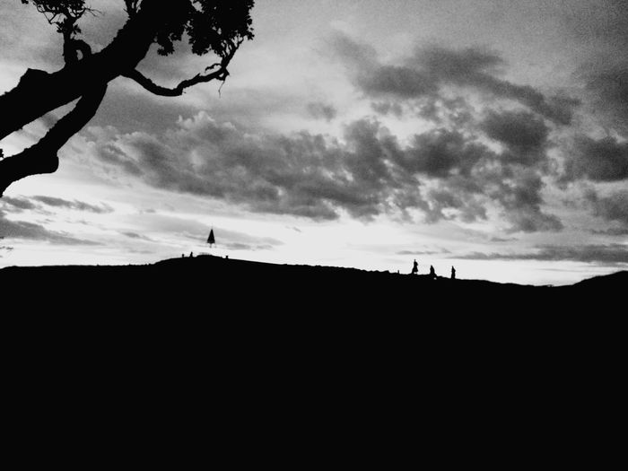 Silhouette man on landscape against sky during sunset
