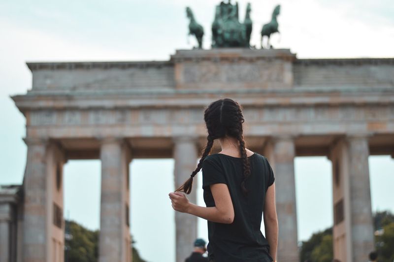 Rear view of young woman standing in front of building