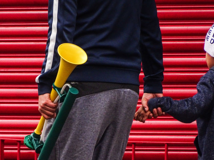 Midsection of father and child with trumpet against shutter